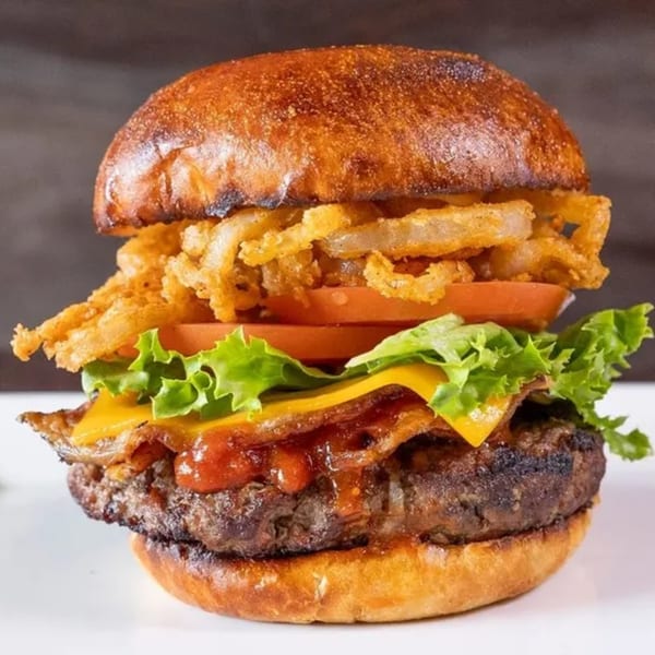 A Frends Brewhouse burger with crispy fried onions, tomato, lettuce, cheese, bacon, and BBQ sauce.