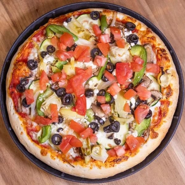 A Frends Brewhouse pizza with tomatoes, olives, green peppers, zucchini, and feta cheese.