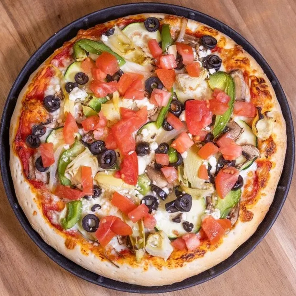 A Frends Brewhouse pizza with tomatoes, olives, green peppers, zucchini, and feta cheese.