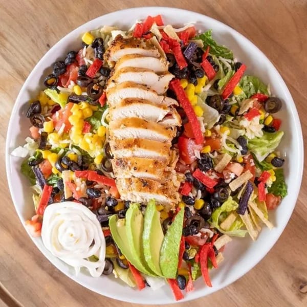 Overhead view of a Frends Brewhouse chicken salad with corn, black beans, avocado, and tortilla strips.