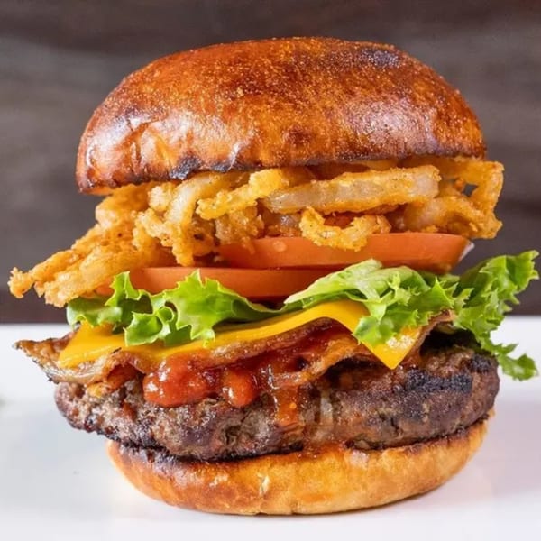 A Frends Brewhouse burger with crispy onions, tomatoes, lettuce, cheese, bacon, and sauce.