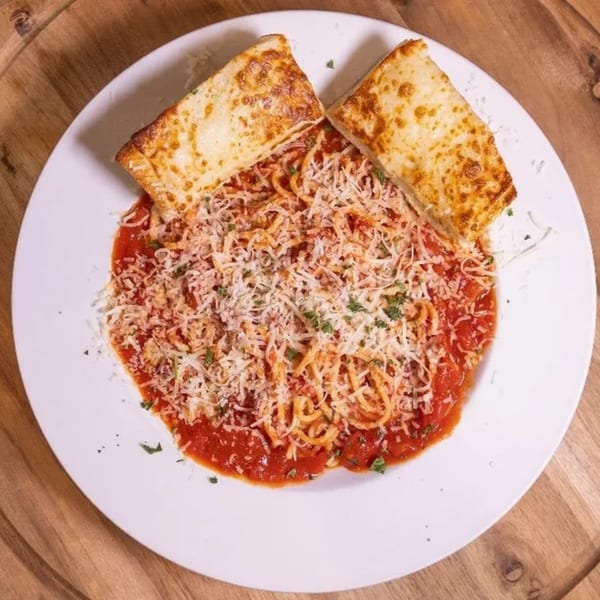 Spaghetti with red sauce, topped with shredded cheese and parsley, served with two slices of garlic bread.