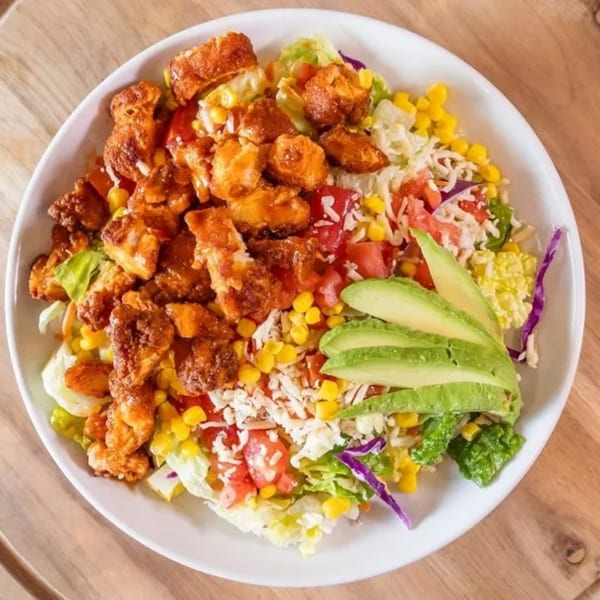 A Frends Brewhouse salad with crispy chicken, corn, tomatoes, cheese, and avocado slices.