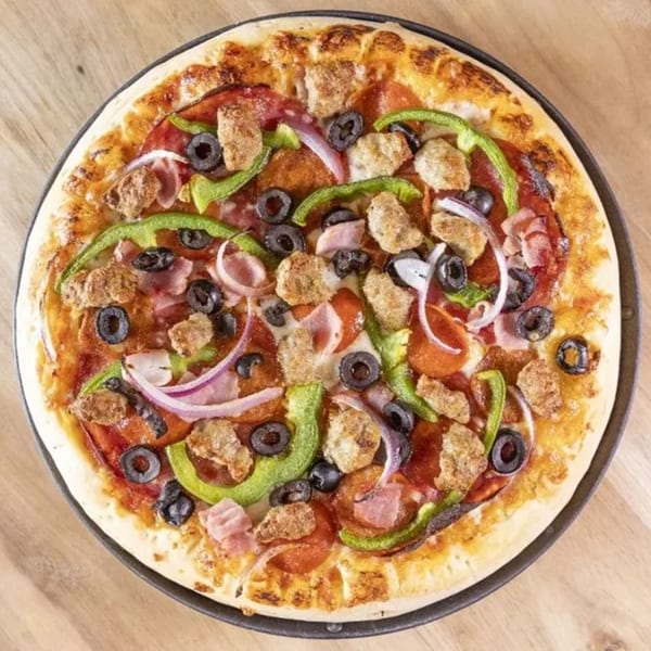 Overhead view of a Frends Brewhouse pizza with pepperoni, sausage, ham, olives, green peppers, and onions.